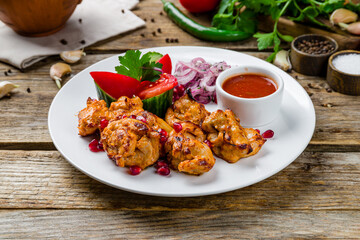 chicken kebab on white plate with tomato sause on old wooden table