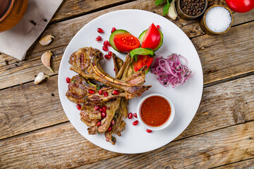 kebab from a rack of lamb with tomato sause on white plate on old wooden table top view