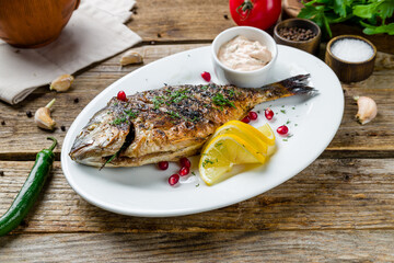 Dorado on grill on a white plate on old wooden table