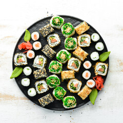 Set of traditional sushi on a black plate. Sushi and rolls on white wooden background.