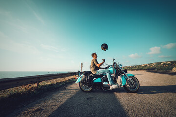 Fototapeta na wymiar Biker on a classic motorcycle tossing the helmet at dusk