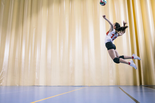 Professional female volleyball player in action serving ball in Madrid, Spain.