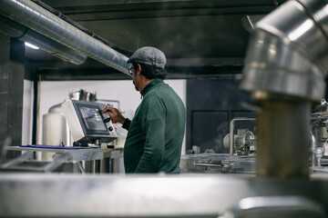 Male brewer setting fermentation tanks on factory