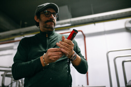 Male brewer using manual hydrometer