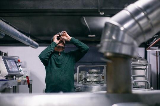 Brewer examining beer in refractometer