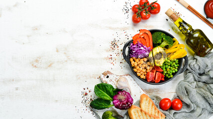 Buddha bowl: chickpeas, avocados, broccoli, paprika, green peas, tomatoes. Vegetable salad. Top view. Free space for your text.