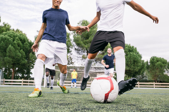 Crop sportive players in motion of running on green grass kickin