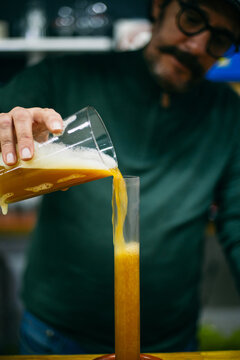 Blurred brewer pouring beer into tube