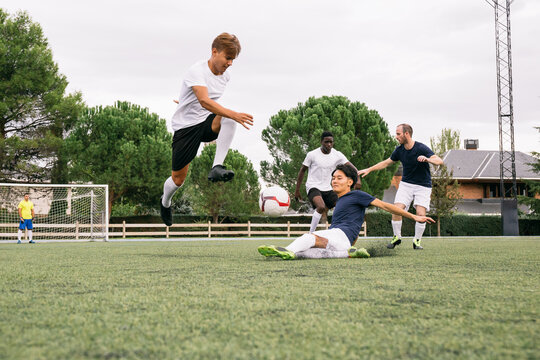 Soccer player avoids incoming slide tackle during a soccer match