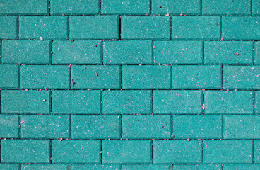 Bright green brick wall with pink splashes and pebbles, abstract brick background