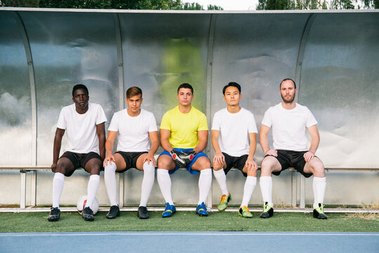 Soccer players sitting on the bench waiting for the match to start