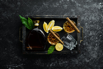 Whiskey in glasses and Cuban cigars on a black stone table. Top view. Free space for your text.