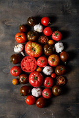 Fresh heirloom variety tomatoes on dark wooden background. Autumn and harvest flat lay.
