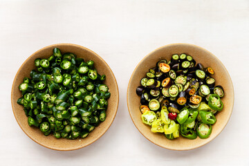 Plate with cut various chili peppers on bright background. Top view with copy space.