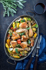 Traditional Mediterranean roasted chicken with fried  vegetable offered as top view in a rustic casserolle