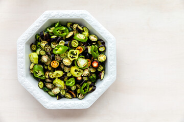 Plate with cut various chili peppers on bright background. Top view with copy space.