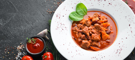 Beef stew with beans and vegetables in a tomato sauce on a plate. Top view. Free copy space.
