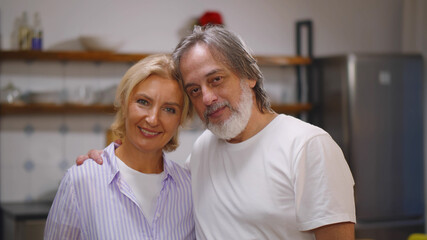 Portrait of cheerful senior couple at home smiling to camera.