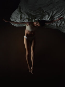 Woman crucifix posture on bed upside-down