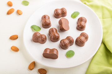 Chocolate candies with almonds on a white wooden background. side view, selective focus