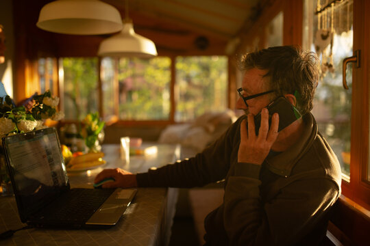 Senior Man Talking On His Mobile Phone At The Table
