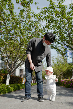 Babygirl walking in cherry garden with father