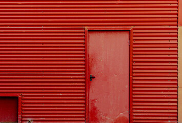 Fachada metálica de almacén industrial con puerta roja