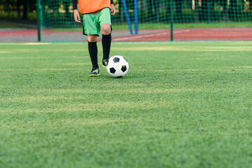 Soccer player kicking ball on field. Soccer players on training session. Close up footballer feet kicking ball on grass.