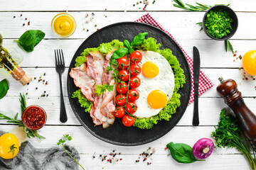 Breakfast. Fried eggs with bacon and cherry tomatoes. Top view. Free space for your text.