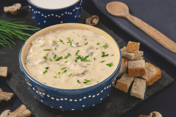 Homemade mushroom cream soup. Served with croutons on a dark background. Close-up view.