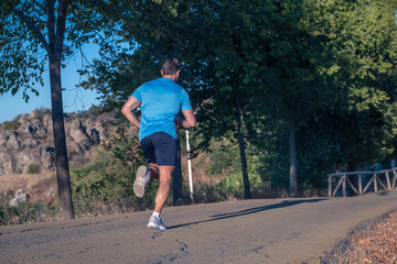 Fototapeta premium Young man in blue t-shirt running through a park