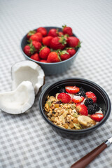 Healthy breakfast Granola with strawberries, banana, nuts and blackberries stands on the table. Ingredients in the background.