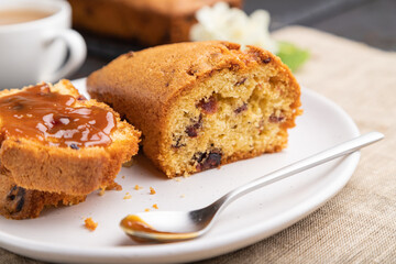 Homemade cake with raisins, almonds, soft caramel and a cup of coffee on a black concrete background. Side view, selective focus.