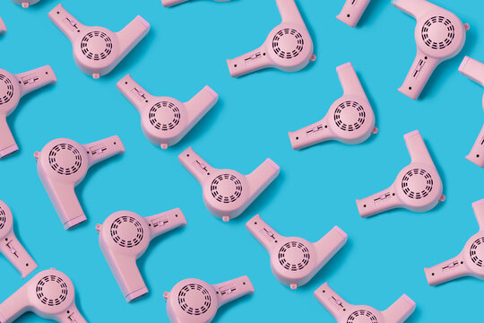 Creative pattern made with pink hair dryers on a blue background. Minimal hairdressing concept. Flat lay.