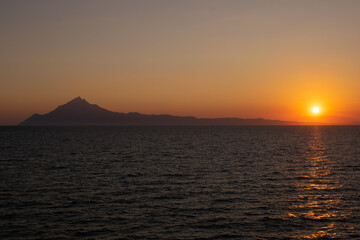 Fototapeta premium Sunste over the Mediterranean horizont in summer seen from a boat with Athos mountain