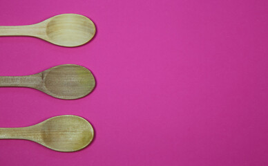 High angle view on three wood spoons on pink background with blank copy space for text