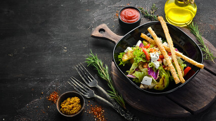 Vegetable salad with chicken, zucchini and feta cheese on a black plate. Top view. Free space for your text.