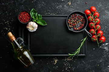Black stone kitchen background. Wooden kitchen board on a black table with spices. Top view. Rustic style.