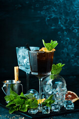 Cocktail with cola. Rum with cola and mint in a beautiful glass. On a black stone background. Menu bar. Alcohol.