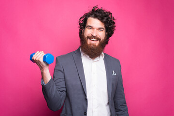 portrait of cheerful handsome man wearing suit and working with small dumbbell, fitness concept