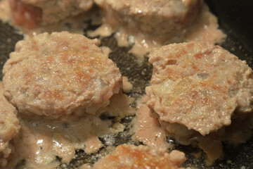 Meat cutlets are fried in frying pan.