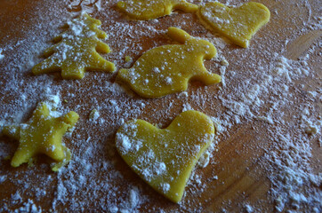 Shortbread cookies of different shapes on a wooden table with flour. Cooking, baking.