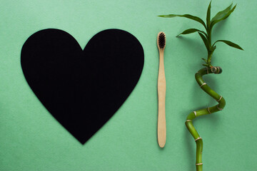 Natural bamboo toothbrush there is a place for text next to the black heart. Zero waste. Ecology and nature protection. Copyspace.