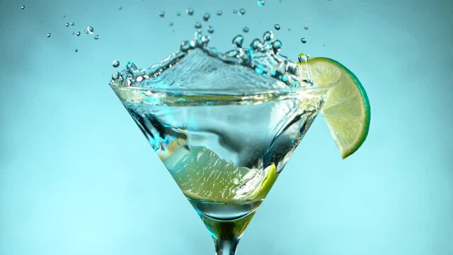 Super Slow motion shot of lime splashing into Dry Martini Drink