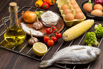 Raw fish with vegetables on grill grate.