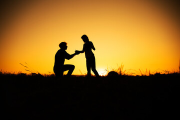 Fototapeta na wymiar Sunset Marriage Proposal. engagement process at a beautiful sunset. Couple in love. 