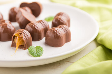 Chocolate candies with almonds and caramel on a white wooden background. side view, selective focus