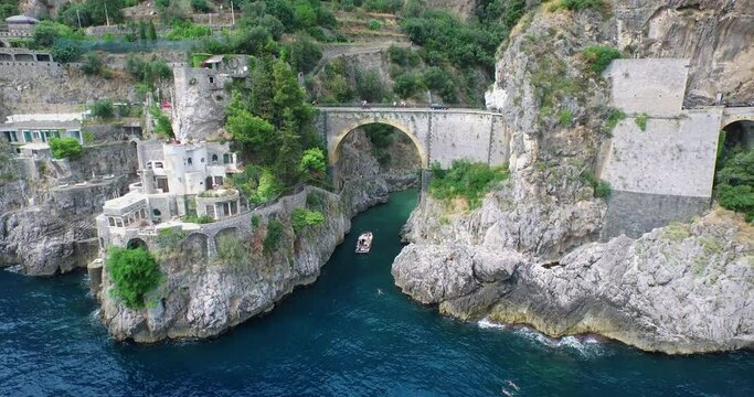 Boat passes underneath Furore Bridge along Amalfi Coast, aerial