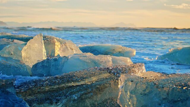 Okulsarlon Beach covered in icebergs at sunset, slow motion close up
