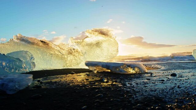 Slow motion, sun sets behind icebergs on Okulsarlon Beach